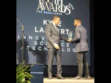  Kyle Lambert receiving his National Youth Award for Excellence in Science and Innovation from Prime Minister Andrew Holdness on the lawns of Jamaica House in February.