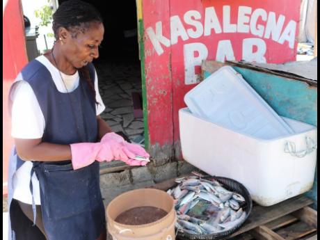 Kathleen Shaw-Gonzales cleans sprats at the Greenwich Town Fishing Village in St Andrew.