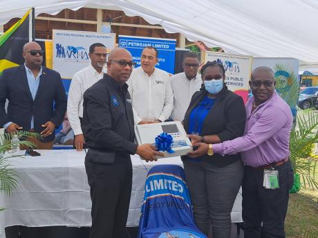 Front row, from left: Colin Barnett, manager of human resource development at Petrojam Limited, presents a donated echo-cardiogram machine to Dr Tanique Bailey-Small, medical officer of health for St James, and Lennox Wallace, the parish manager for St Jam
