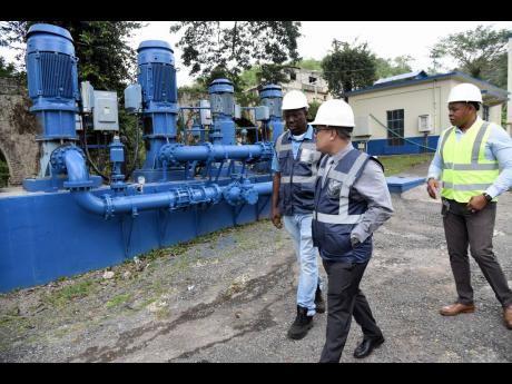 Patrick Gordon (left), production supervisor at the Constant Spring Water Treatment Plant in St Andrew, leads Matthew Samuda (centre), minister without portfolio in the Ministry of Economic Growth and Job Creation, on a tour of the Constant Spring Clearwat