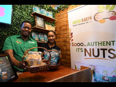 Damani Johnson, brand manager of Green Earth Peanut Company Limited, and Shenisea Francis, business development officer, show off come of the company’s products at the 2023 Expo Jamaica at the National Arena in St Andrew last Friday.
