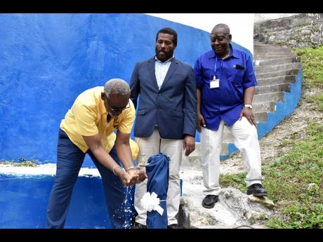 Desmond McKenzie, minister of local government and rural development prepares to drink water from a standpipe attached to the Ashton Catchment tank in Westmoreland on April 27. Looking from left are Daniel Lawrence, member of parliament for Westmoreland Ea