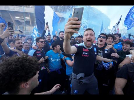 Napoli fans cheer in front of the Diego Armando Maradona stadium in Naples, Italy yesterday after the club clinched the Italian title.
