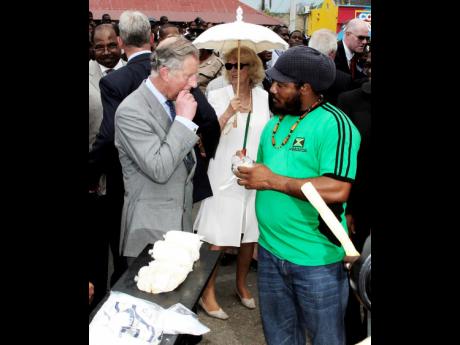 The Prince of Wales samples sugar cane from vendor Carlos Morgan during the visit of Their Royal Highnesses to the Falmouth town square in Trelawny. In background is the Duchess of Cornwall. Charles succeeded his late mother to become King. 