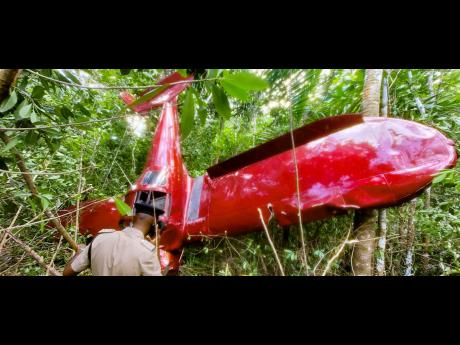 A police officer looks at the plane which crashed into bushes in the Ballard’s Valley area of Highgate, St Mary, yesterday morning, and resulted in the death of of Major Dudley Beek.