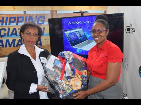 Tsahai Morgan (right), ADVANTUM communication and marketing executive, presents a  gift basket to this fortunate patron on Day 2 of Expo Jamaica.