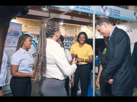 Prime Minister Andrew Holness (right) shares a light moment with Shipping Association of Jamaica exhibitors at their booth.