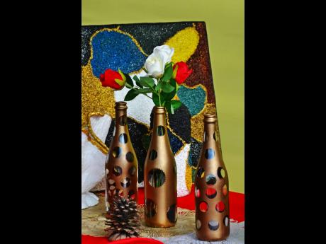 Discarded champagne bottles now used as vases, with a wall plaque, made of rice, in the background.