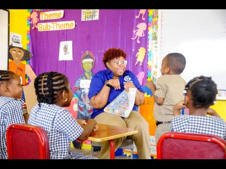 Raquel McLean, a representative from The Gleaner, reads a story called ‘Myself as a Dinosaur’, as Gabriel Sinclair (second right) and other students react, at St Paul’s United Infant School on Lockett Avenue, Kingston 4, as part of the Read Across Ja