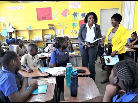 Discovery Bauxite attorney-at-law Trudy-Ann Fisher (standing, left) enjoying a reading session with a grade-six class at Discovery Bay All-Age School on Tuesday during Read Across Jamaica Day. The legal officer read from a book ‘Jonah – The Man Who Tri