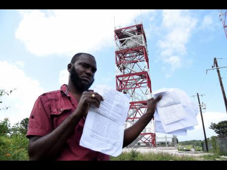 
Farmer Kerron Outar shows the documents for the deed of gift for the land in Cocoa Walk in Cross Keys, southern Manchester where the JDF built a cell tower.