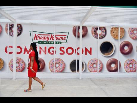 A woman walks past the Krispy Kreme Doughnuts store on Waterloo Road in St Andrew.