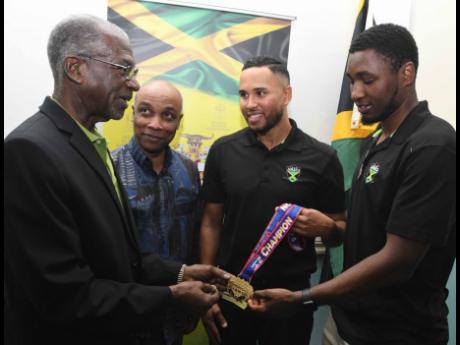 (From left) Jamaica Ice Hockey Federation president Don Anderson, Jamaica Olympic Association president, Christopher Samuda, and Jamaica men’s ice hockey team co-captains Jaden Lindo and Teegan Moore admire one of the players’ gold medals that was won 