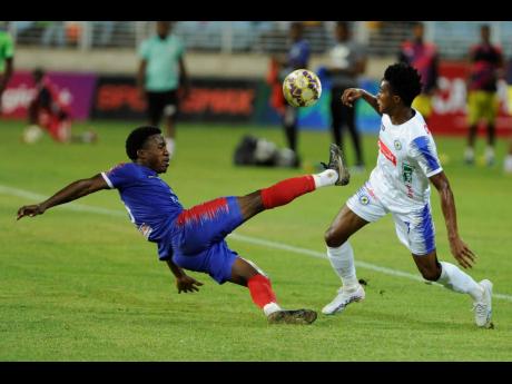 Nickoy Christian (left) of Dunbeholden FC tackles Devonte Campbell of Mount Pleasant during the Jamaica Premier League first leg quarterfinal match at Sabina Park yesterday. The game ended in a 1-1 draw. 