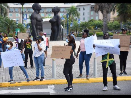 Scores of persons yesterday turned up outside the Emancipation Park in New Kingston to protest against a pay hike for politicians announced by Dr Nigel Clarke, minister of finance and the public service, in Parliament on Tuesday.