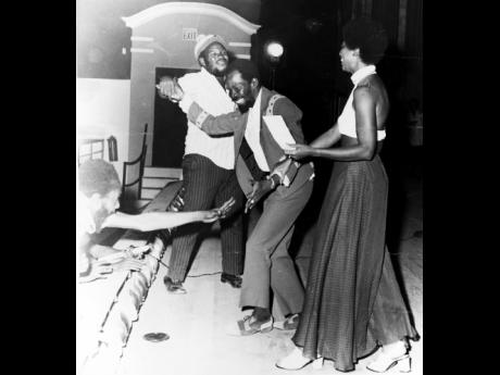 WINNER: Joe Higgs, winner of the Jamaica Tourist Board’s Tourist Song Competition, being congratulated by two of his admirers, while Mrs Michael Manley, wife of the prime minister, tries to present him with his prize cheque for $1,000.