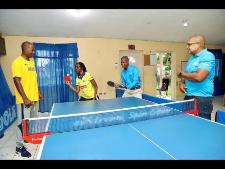 
Le-Anna Smith (second left), teaches Flow’s Community Program Coordinator, Courtney Bell, the perfect serve at the Angels Table Tennis Academy in Spanish Town last year. 
