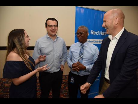 Sandra Forero (left), product manager, Red Hat, speaks with Andres Pardo (second left), partner, accounts manager, Unified Technologies; Rob Eyers (right), senior vice president for  business development at Unified Technologies; Leighton ‘Ali’ Palmer (