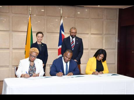 From left (seated): Maureen Dyer (left), acting permanent secretary at the Ministry of Youth and Education; Damion Campbell, British Council country director, Jamaica and the Caribbean islands; and Latoya Harris-Ghartey sign a memorandum of understanding b