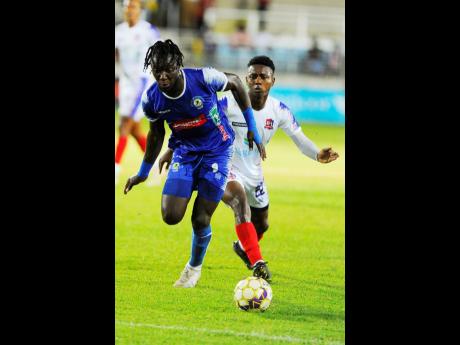 
Trivante Stewart (left) of Mount Pleasant dribbles past Zackiya Wilks of Dunbeholden during their Jamaica Premier League (JPL) match at Sabina Park tonight. Harbour View won 3-0 to advance to the semi-finals 4-1 on aggregate.