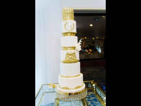 Towering in regal gold and white is the Elliotts’ wedding cake, made with love by Sweet Mischief Ja.