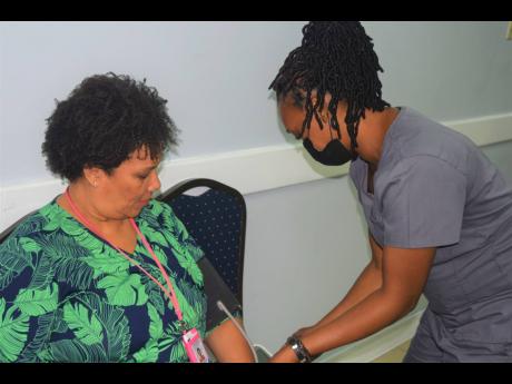 Vice-President of the Shipping Association of Jamaica, Corah Ann Robertson Sylvester (left), gets her blood pressure checked by Newport Medical Group’s Nurse Burke during the body’s complimentary screening on World Hypertension Day.