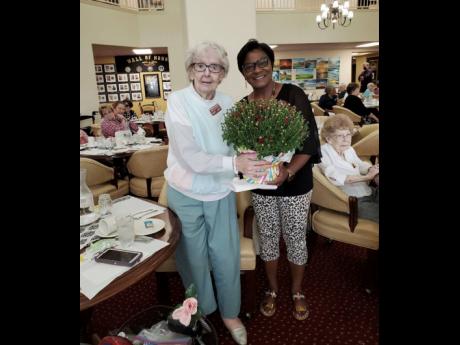 Paulette Williams-Thompson presents a floral arrangement to Mary Jean on grandparents’ day, at Hearts and Hands United’s annual Christmas mingle.