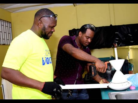 Lincoln Toques, from the Electrical Technology department at Irwin High school and Ian Williams, from the  Jamaica Public Service (JPS) prepare to install a ceiling fan at the Irwin High School in St. James on Labour Day, Tuesday May 23.
