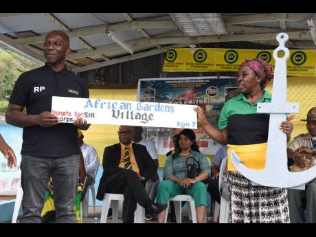 Rudi Page (left), CEO, Making Connections Work, and Dorothy Blaine Price-Maitland, community organiser and host and organiser of WindRush 75 Five Communities Anchor Festival in August Town, show off the community sign and anchor during the festival on Labo