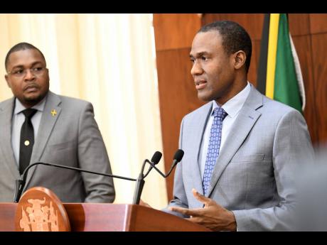 Dr Nigel Clarke (right), minister of finance and the public service speaks while Robert Morgan, minister without portfolio with responsibility for information, Office of the Prime Minister looks on at the post cabinet press briefing at Jamaica House yester