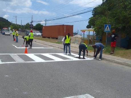 HEART/NSTA  Trust volunteers paint a pedestrian crossing on the main road opposite the Sandy Bay Basic School.