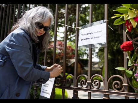 An unidentified woman fixes notes on the gate of the house of late singer and stage performer Tina Turner in Kuesnacht, Switzerland, on Thursday.