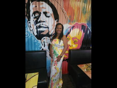 With Peter Tosh and Dennis Brown as her backdrop, Guardian Life’s Dollis Campbell poses for the camera at the S Hotel’s Roots Rock restaurant.