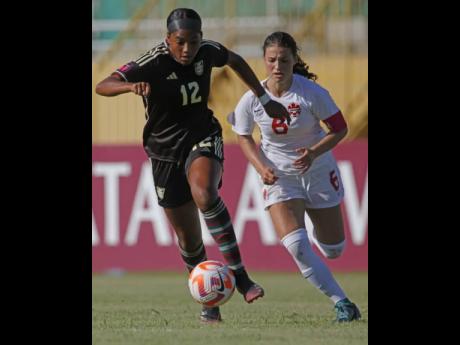 Young Reggae Girl Maya Ragunandanan dribbles away from Canada's Thaea Mouratidis during their Concacaf Under-20 Women's Championship game at the Estadio Felix Sanchez in the Dominican Republic earlier today.