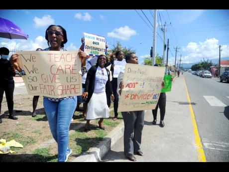 Teachers across Kingston and St Andrew hold placards while demonstrating in front of the Ministry of Finance and the Public Service at Heroes ‘Circle yesterday.