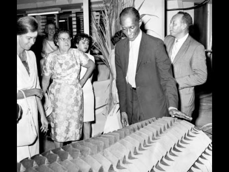 In this 1963 photo, then Minister of Trade and Industry Robert Lightbourne examines a sugar mill at the third Industrial Exhibition of the Jamaican Manufacturers’ Association. The sugar mill roller was made by Kingston Industrial Works for export to Peru