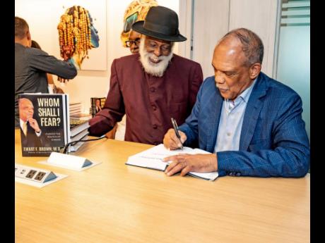 Dr Ewart Brown, former premier of Bermuda, signs a copy of his book, ‘Whom Shall I Fear?’ for Everton Bird, attorney-at-law, during a Fireside Chat and Book Signing event at the AC Marriott Hotel in St Andrew on Friday. 