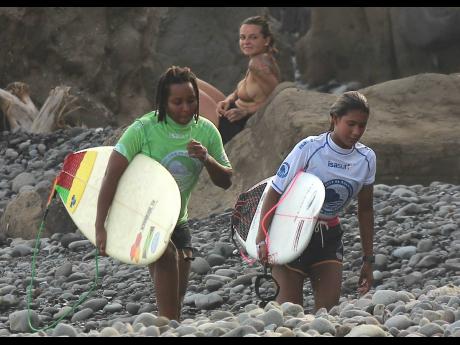 Jamaica's Imani Wilmot (left) and Isabel Higgs of Thailand leave the beach after completing heat 22 in the women's opening round at the ISA World Surfing Games at La Bobana in El Salvador today.