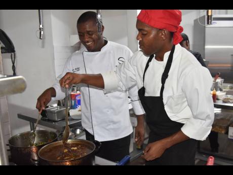 Executive Chef Maurice Mullings (left) and cook Jeff Morris put the finishing touch on the oxtail.