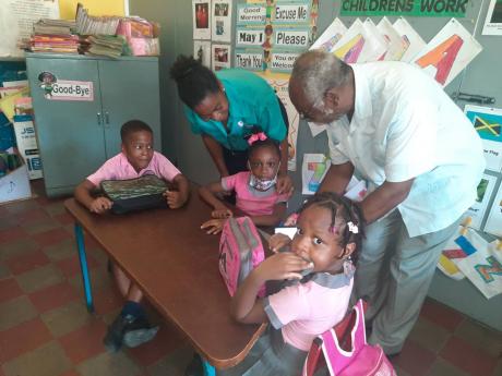 Pastor Rennard White and daughter, Renae, interact with students at the early childhood development institution at Tower Hill Missionary Church in West Central St Andrew.