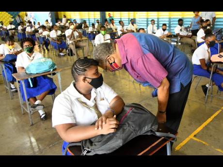 In this 2020 photo, Dr Peter Phillips, former PNP president, speaks with a student sitting for primary exit examinations at Tarrant High School.