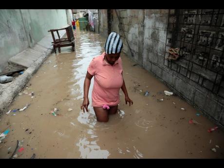 A woman walks through a flooded alleyway after heavy rain in Port-au-Prince, Haiti, on Saturday.