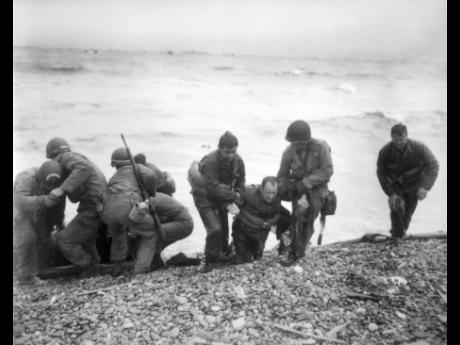 Members of an American landing unit help their comrades ashore during the Normandy invasion on June 6, 1944, near Sainte-Mere-Eglise. The D-Day invasion that helped change the course of World War II was unprecedented in scale and audacity. Veterans and wor