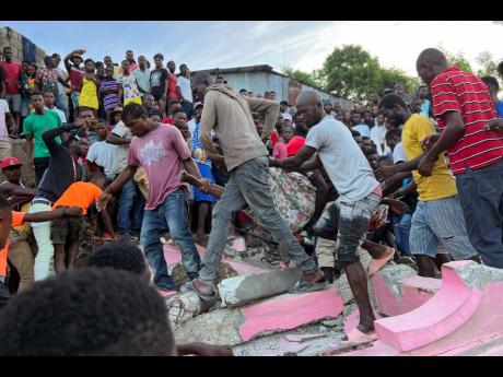People carry an injured person away from a home that collapsed due to an earthquake in Jeremie, Haiti, on Tuesday, June 6.