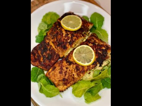 Stuffed jerk salmon laying on a bed of fresh greens.