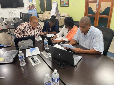 Community liaison officers at the Caribbean Development Bank’s Basic Needs Trust Fund (from left): Jackie Allain (St Lucia), Cher Akoi (Suriname), and Cecil Browne (Montserrat) focus on their group activity during the gender training workshop in Barbados