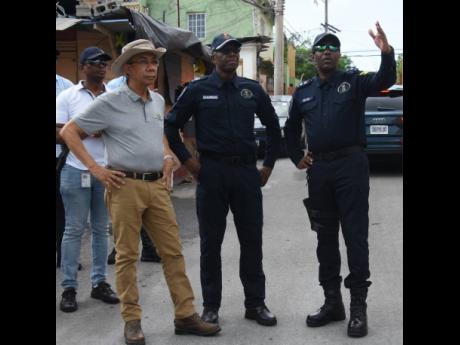 In this file photo Vernon Ellis (right), Senior Superintendent of Police, gesticulates while speaking with Dr Horace Chang, National Security Minister, and Clifford Chambers, Assistant Commissioner of Police, during a tour of the community of Mount Salem i