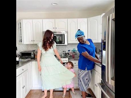 Adina Azarian beckons her daughter Aria, while Evadnie Smith (right) looks on, as they stand in the kitchen.