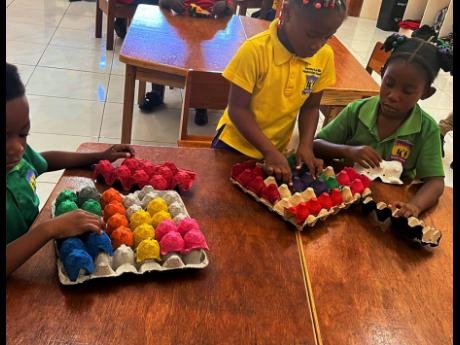K3 students (from left) Jaheem Webb, Renice Haughton and Alayna Lewis having puzzle time with recycled egg trays.