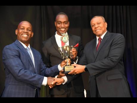 Lambert Johnson (left), president of the Jamaica Co-operative Credit Union League, presents the Renford Douglas trophy for Credit Union of the Year to Dwight Sommers (centre), director of the Jamaica Police Credit Union, and Wray Palmer, general manager of